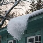 Big patch of snow being pushed off the roof with shovel