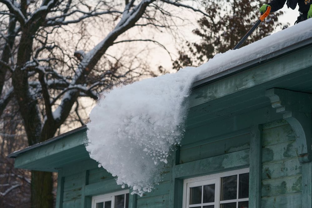 Big patch of snow being pushed off the roof with shovel