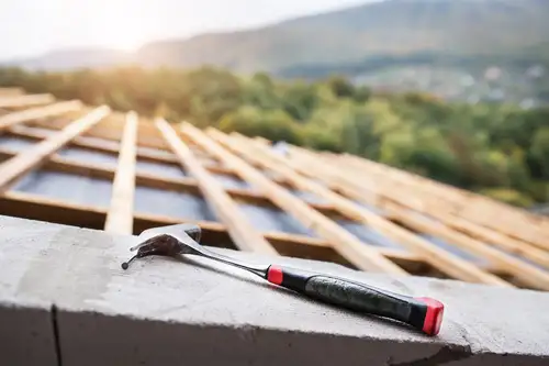7_Tips_to_Maintain_Your_Roof_and_Make_It_Last_Roofing_Construction_Aurum_Contracting_WI_and_IL Roof Replacement or installation construction project that's half way done and hammer in the foreground